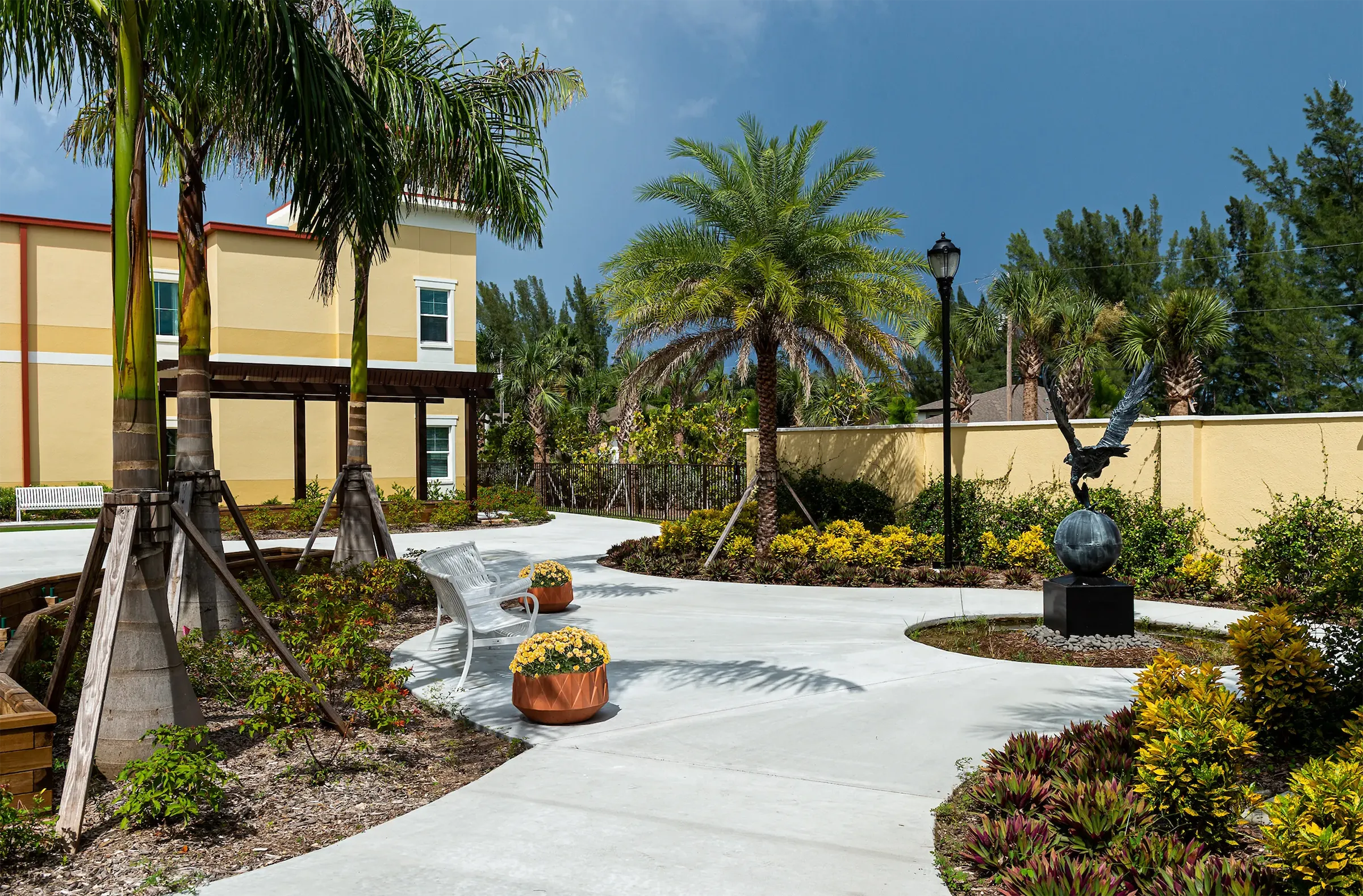A courtyard with palm trees and a sculpture of a bird at The Gallery at Cape Coral.