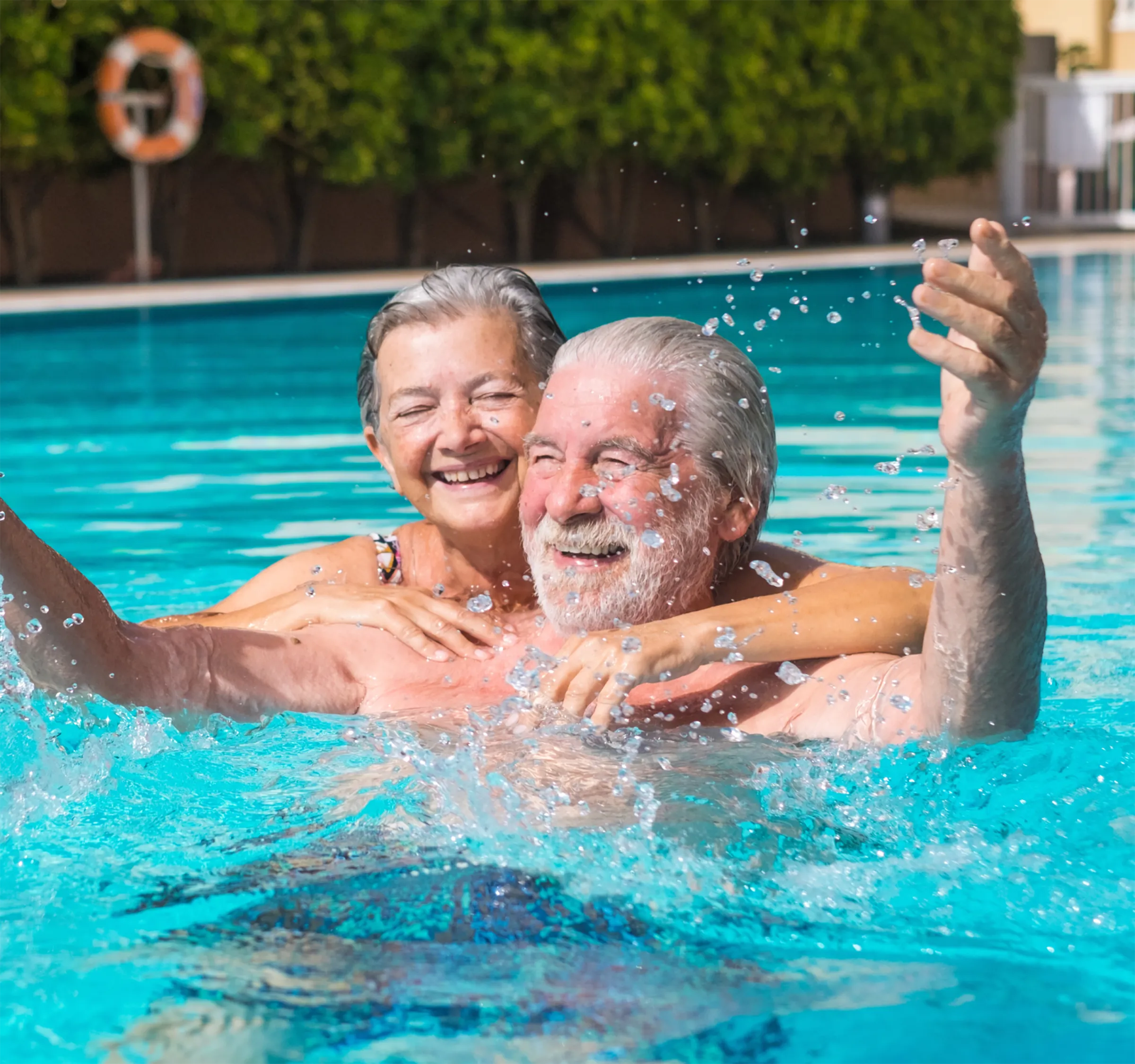 An Independent Living couple smiling and hugging while swimming in a pool.