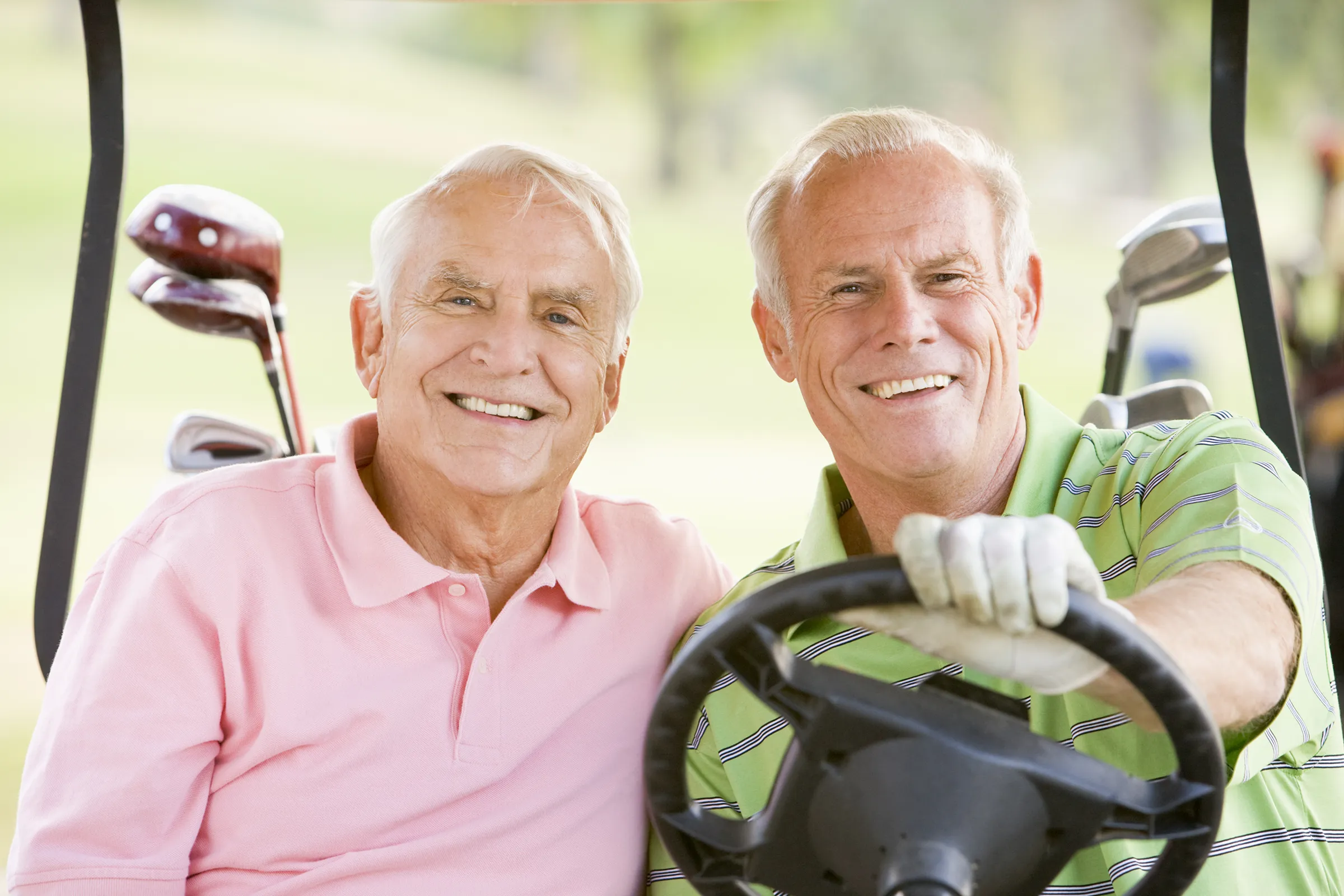 two men in a golf cart smling for camera.