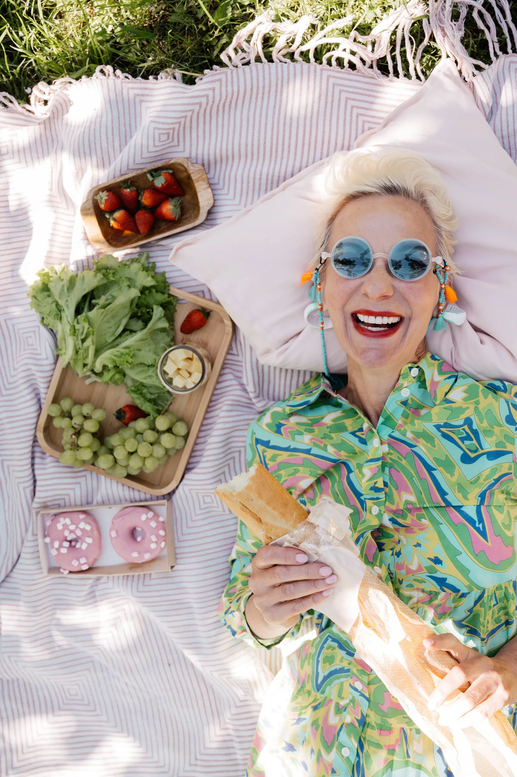 woman outside laying on a blanket with a loaf of bread smiling