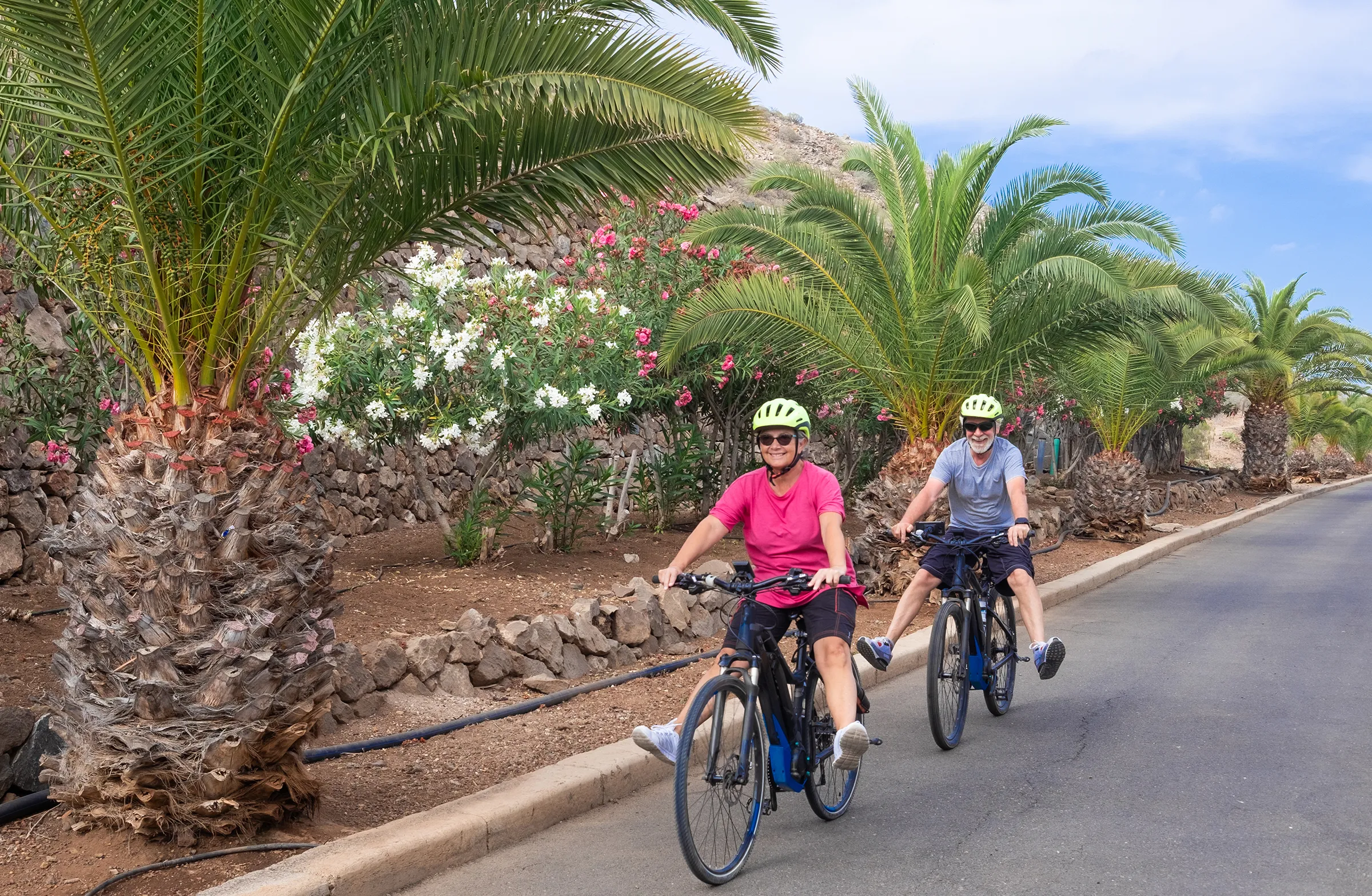happy couple enjoying a bike ride next to large palm trees in florida