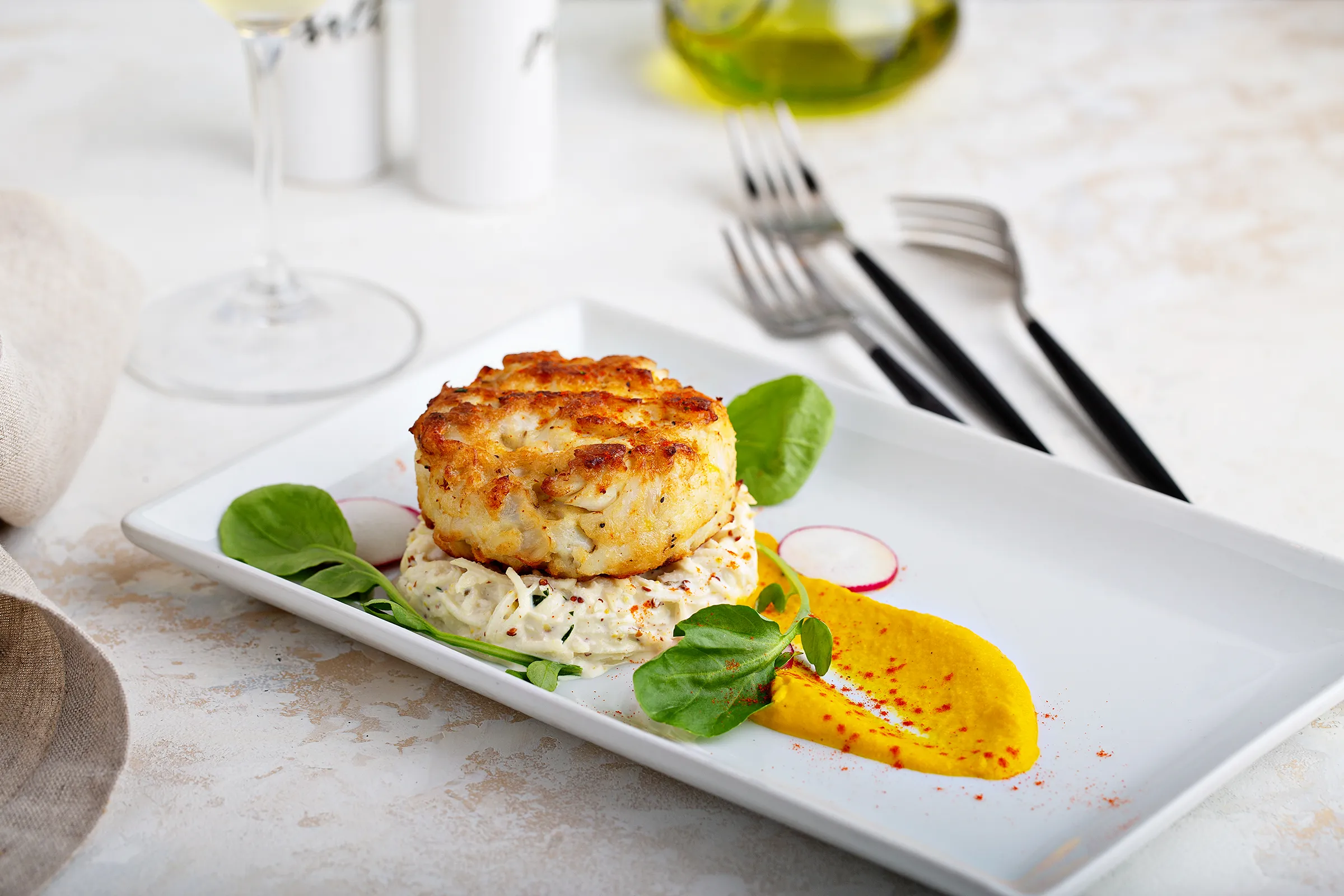 fresh crab cake plated with yellow sauce over rice