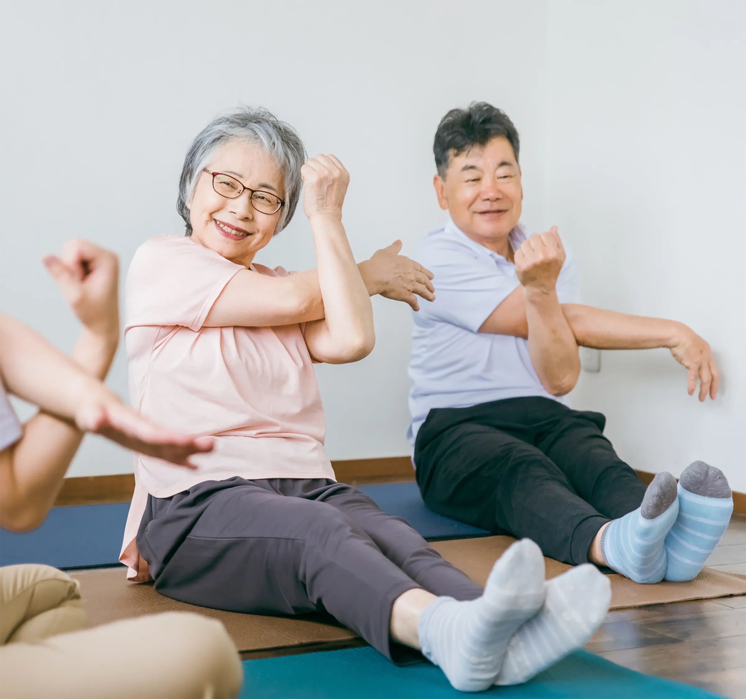 Two Independent Living residents stretching on yoga mats in an engaging fitness class at The Gallery.